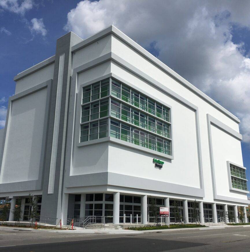 Modern white storage facility with large windows under a blue sky.