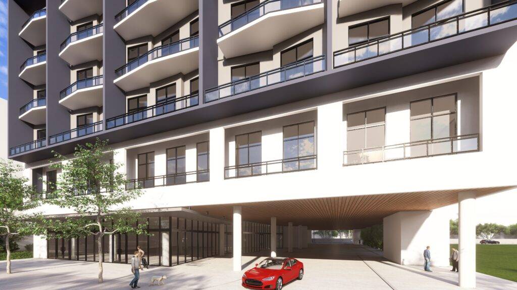 Modern urban building with balconies and a red car parked underneath.