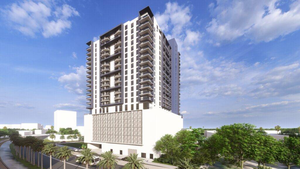 Tall modern apartment building with balconies against a blue sky, surrounded by greenery.