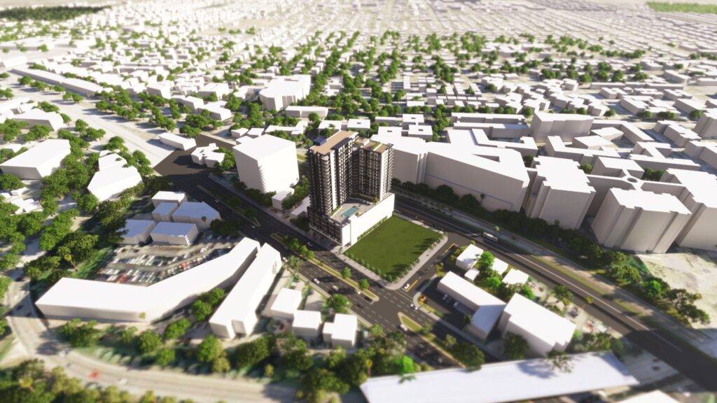 Aerial view of a modern urban landscape with a tall building dominating the center, surrounded by streets and green areas.