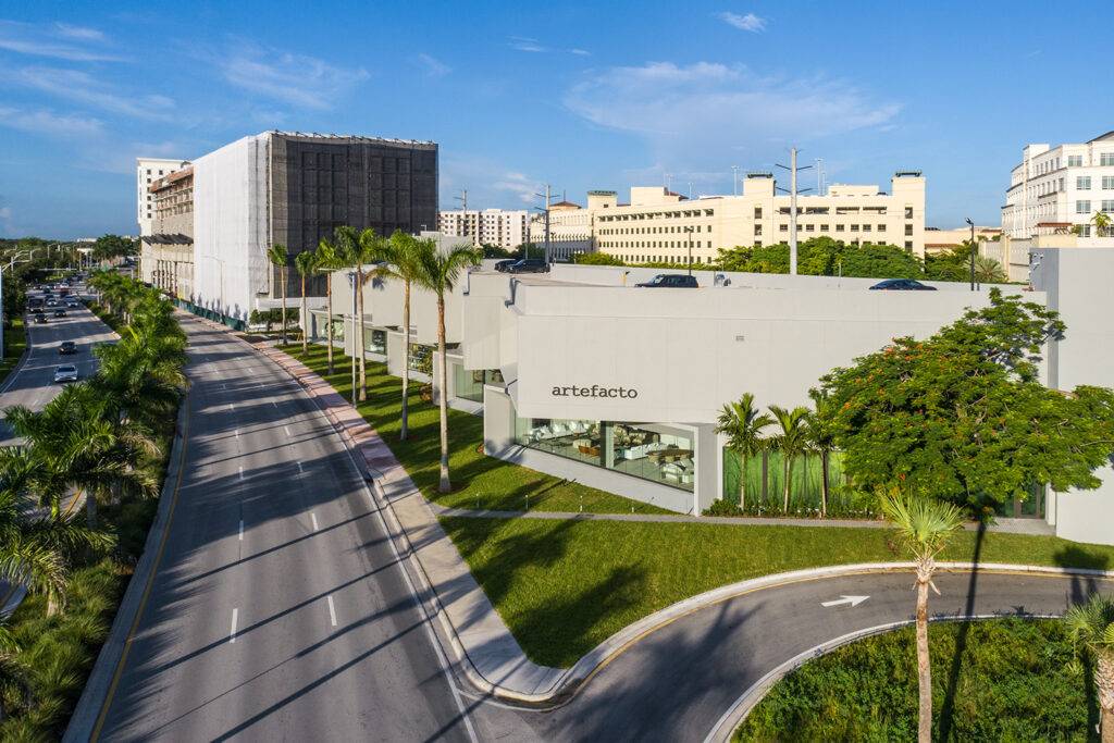 Aerial view of Artefacto Coral Gables showroom surrounded by lush greenery, palm trees, and city buildings.