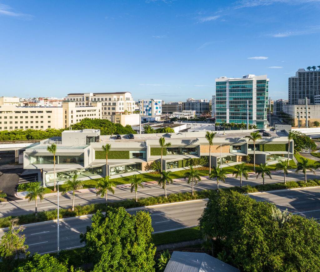Aerial view of modern showroom buildings surrounded by palm trees in Coral Gables.