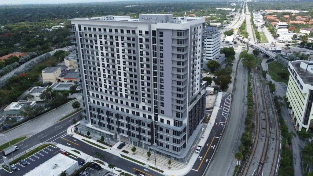 Aerial view of a modern high-rise building surrounded by roads and greenery, capturing urban architecture.