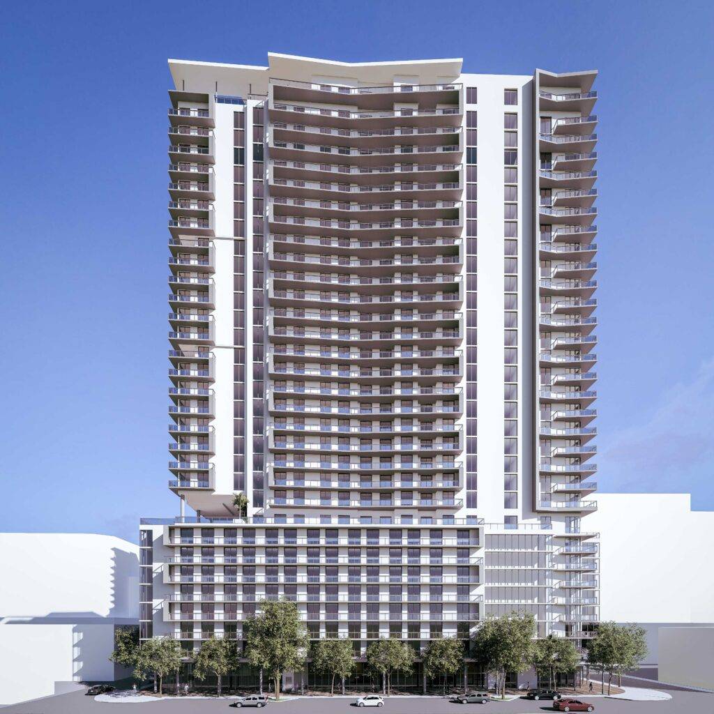 Modern high-rise building with a wave-like facade against a clear blue sky, surrounded by smaller structures and trees.