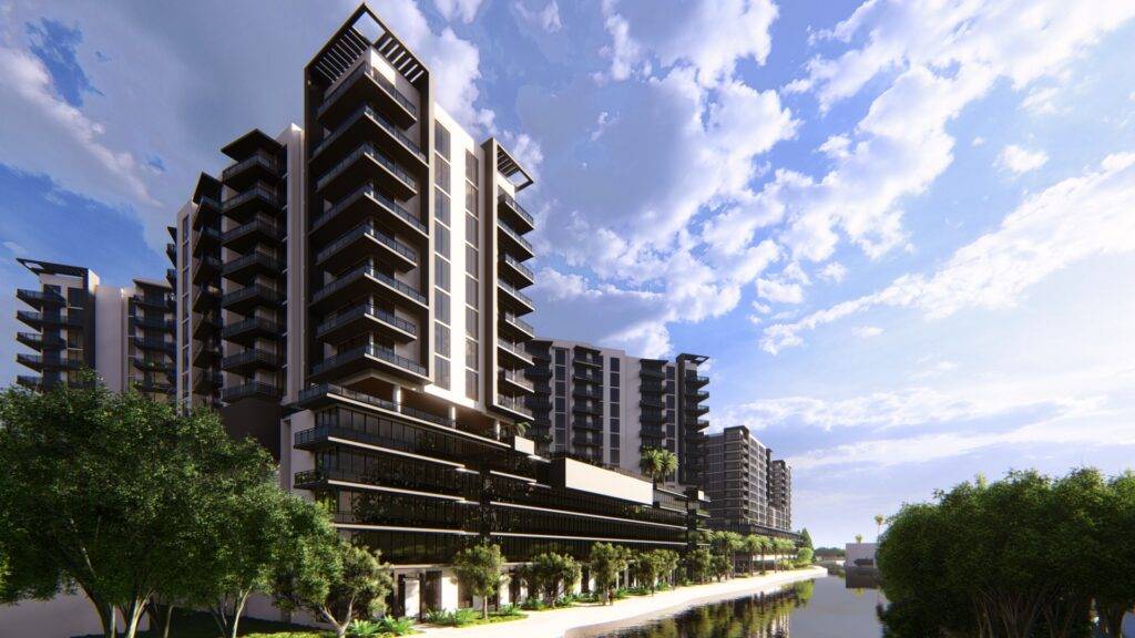 Modern apartment complex with lush greenery and a bright blue sky.