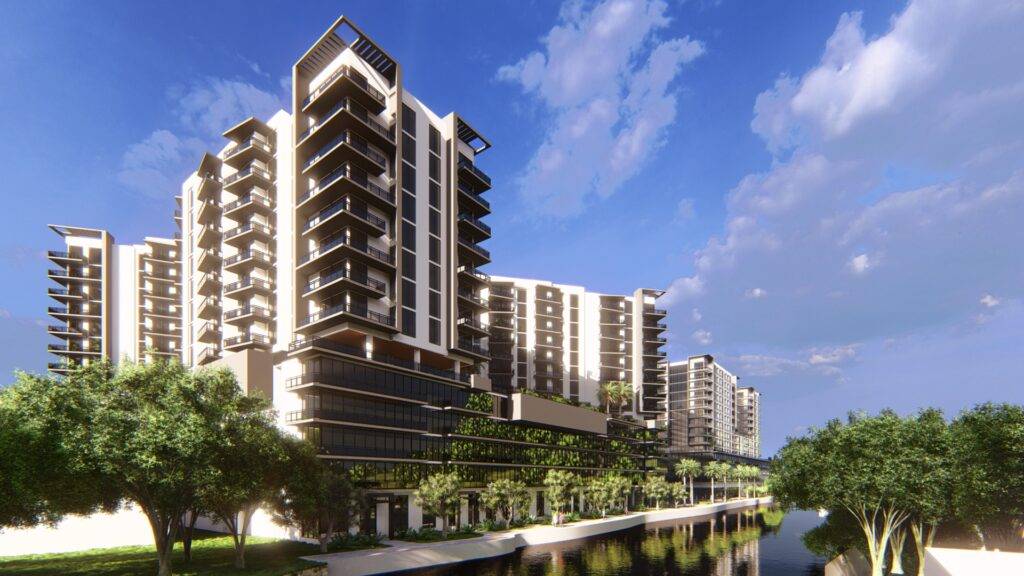 Modern apartment complex with lush greenery and reflective water under a clear blue sky.