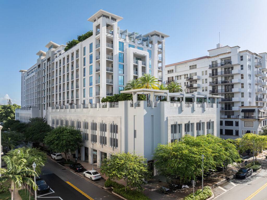 Modern high-rise building with lush rooftop gardens and surrounding greenery on a sunny day.