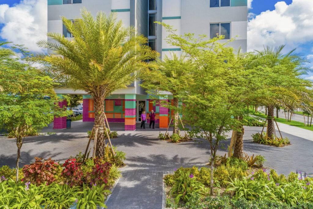 Vibrant Caribbean Village Apartments with lush greenery and colorful facade.