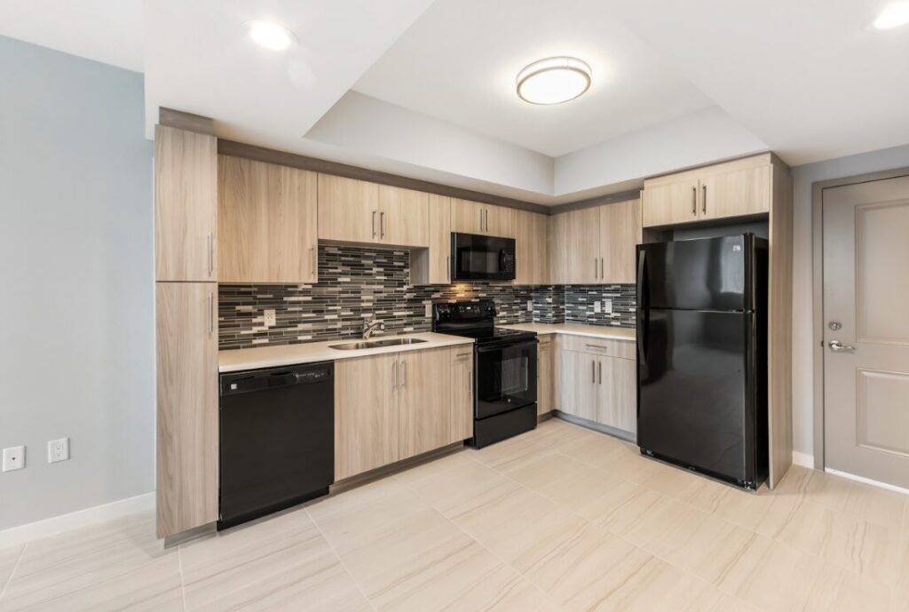 Modern kitchen with wooden cabinets, black appliances, and tiled backsplash.