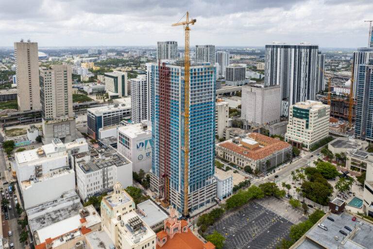 Aerial view of Namdar Towers under construction in a bustling cityscape with cranes and modern high-rises in the background.