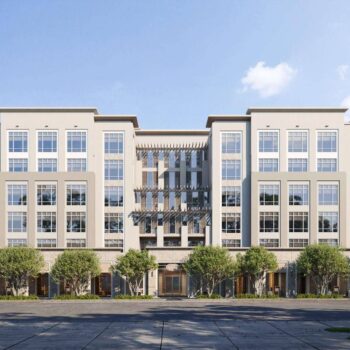 Modern six-story commercial building with large windows and trees lining the street.
