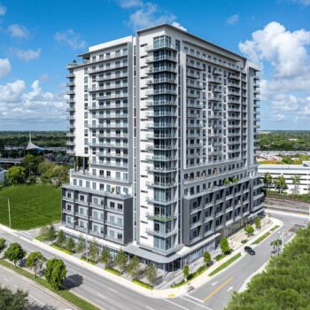 Modern high-rise building with a sleek design under a bright blue sky.