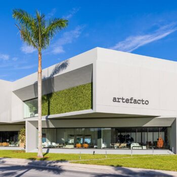 Modern facade of the Artefacto Coral Gables showroom with palm trees and blue sky.