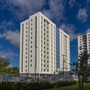 Modern high-rise apartment buildings under a vibrant blue sky with scattered clouds.