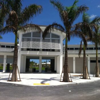 Modern community center surrounded by palm trees on a sunny day.