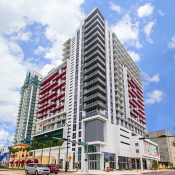 Modern high-rise building with bold red accents against a bright blue sky.