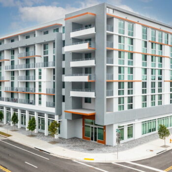 Modern apartment building with white and orange accents on a sunny day.