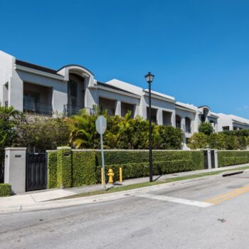 Modern row of townhouses with lush greenery under a clear blue sky.