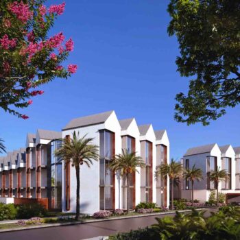 Modern architectural complex surrounded by palm trees and vibrant greenery under a clear blue sky.