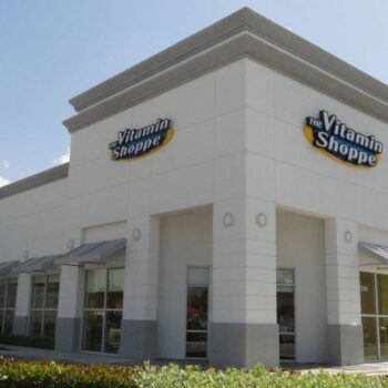 Exterior view of a Vitamin Shoppe storefront with signage and clear blue sky.