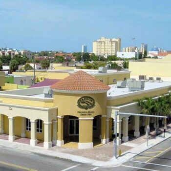 Aerial view of a vibrant yellow building amidst a bustling street in a sunny urban neighborhood.