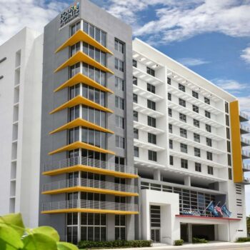 Modern multi-story building with yellow balconies against a blue sky.