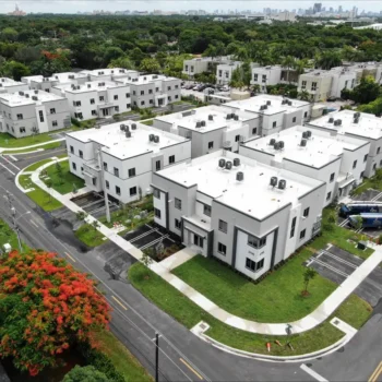 Aerial view of a modern residential neighborhood with white homes and lush greenery.