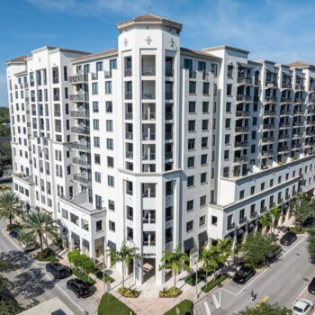 Elegant multi-story white building with palm trees in an urban setting.