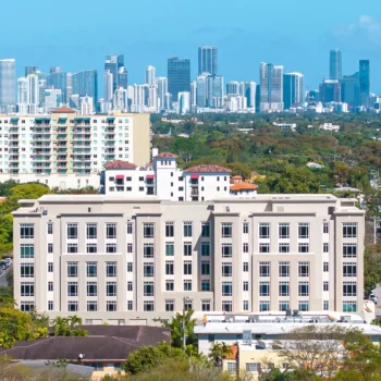 Urban skyline featuring a modern building with a backdrop of skyscrapers and clear blue skies.
