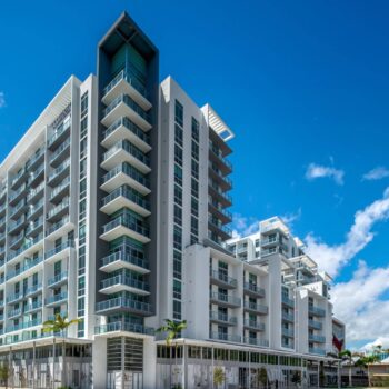 Modern high-rise apartment building under a vibrant blue sky, showcasing contemporary architecture and clean lines.