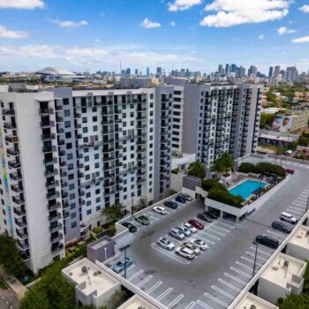 Modern apartment complex with rooftop pool and city skyline in the background.