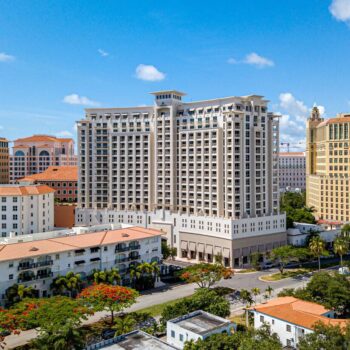 Aerial view of a grand hotel surrounded by urban architecture under a bright blue sky.