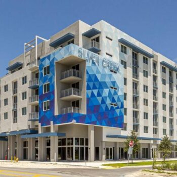 Modern blue and white geometric apartment building with balconies on a sunny day.