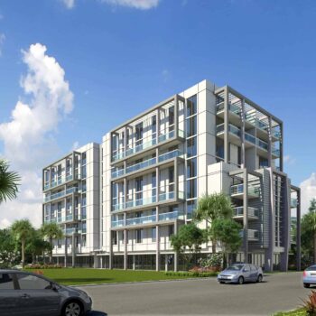 Modern multi-story building with glass balconies and surrounding palm trees under a clear blue sky.