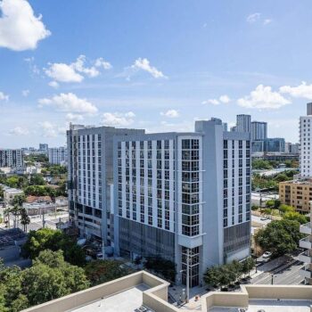 Aerial view of modern cityscape with tall buildings under a blue sky.
