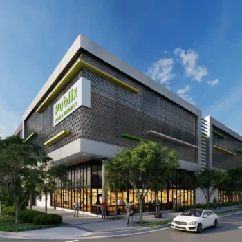 Modern architectural building under a clear blue sky with vibrant greenery and cars on the road.