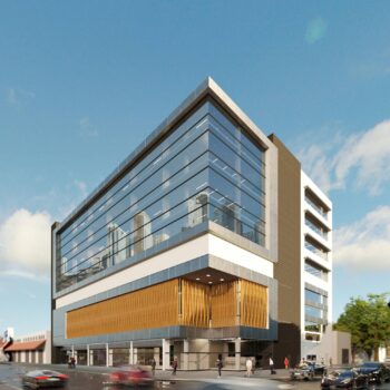 Modern glass office building with street view and cars passing by.