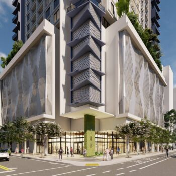 Modern high-rise building with architectural design and lush greenery on a sunny day.