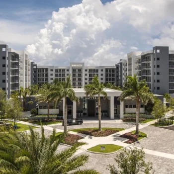 Modern residential complex with palm trees and a bright blue sky