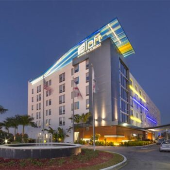 Modern hotel exterior at twilight with sleek design and illuminated signage.