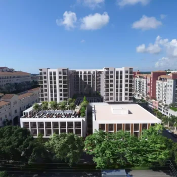 A modern urban landscape with high-rise buildings and lush greenery under a bright blue sky.