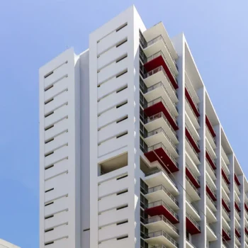 Modern apartment building with red balconies against a clear blue sky.