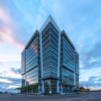 Modern glass skyscraper against a vibrant evening sky.
