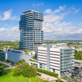 Modern high-rise building with lush greenery and clear blue sky