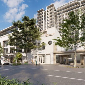 Modern urban architecture with tall glass buildings and lush greenery under a clear blue sky.